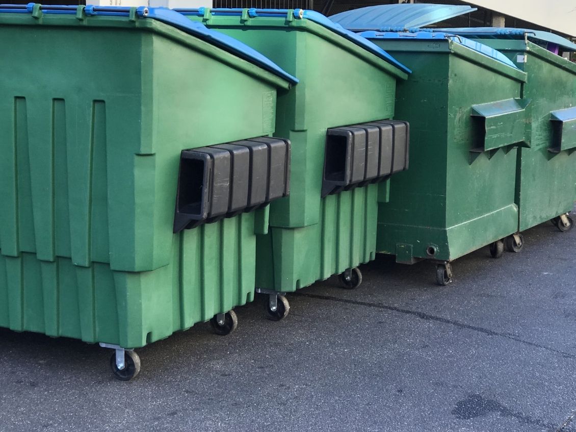 Single Big Green Plastic Dumpster Full Of Trash In A Dirty Yard